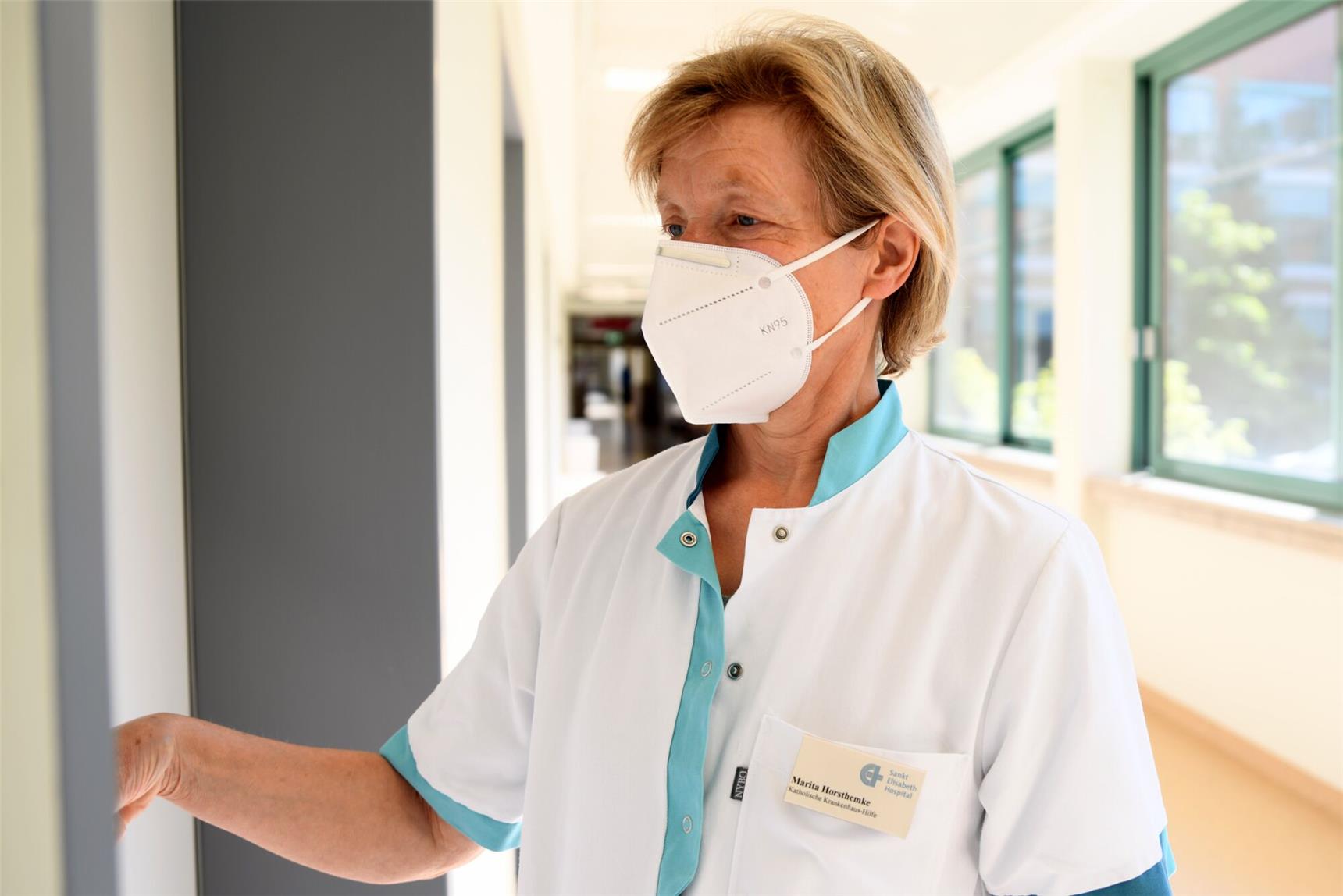 eine Frau mit Maske geht zu einer Tür hinein
